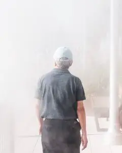 man walking towards smoke-covered building